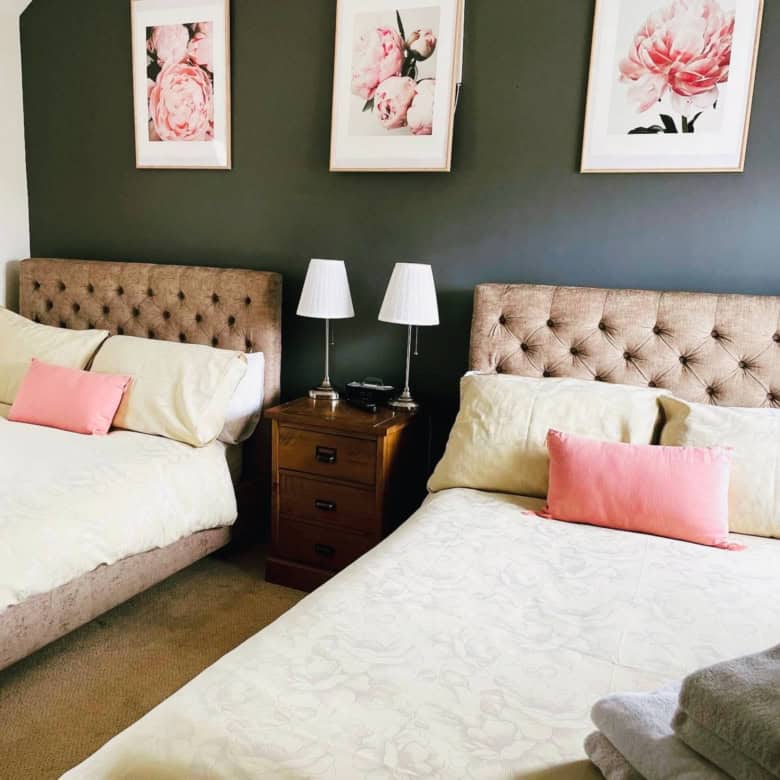 Comfortable bedroom with twin beds, floral artwork, and bedside lamps.