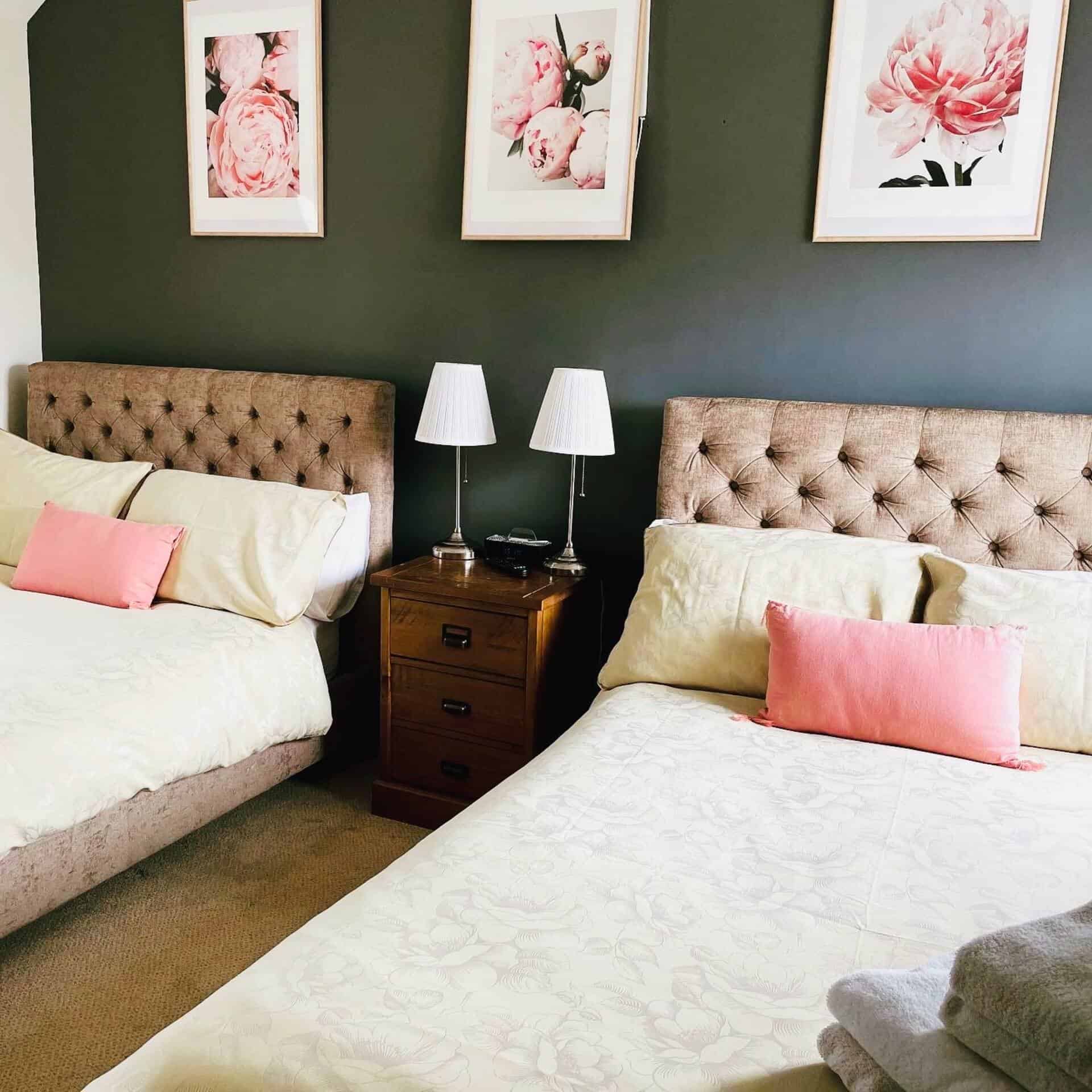Cozy Bedroom with Floral Wall Art Comfortable bedroom with twin beds, floral artwork, and bedside lamps.