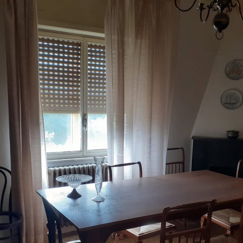 Bright interior with large window and classic furniture in Sardinian apartment.