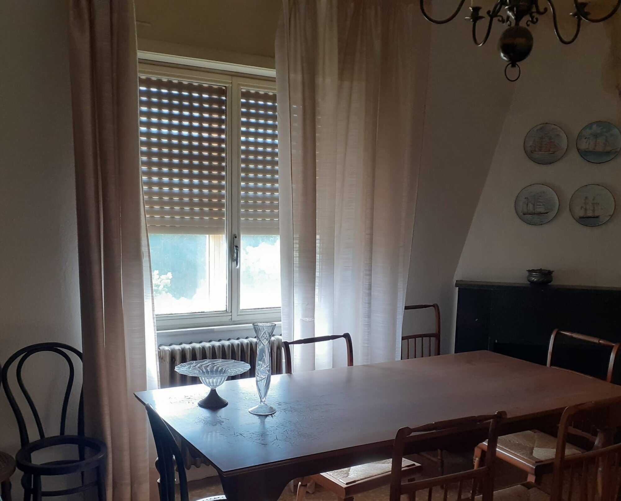 Bright interior with large window and classic furniture in Sardinian apartment.