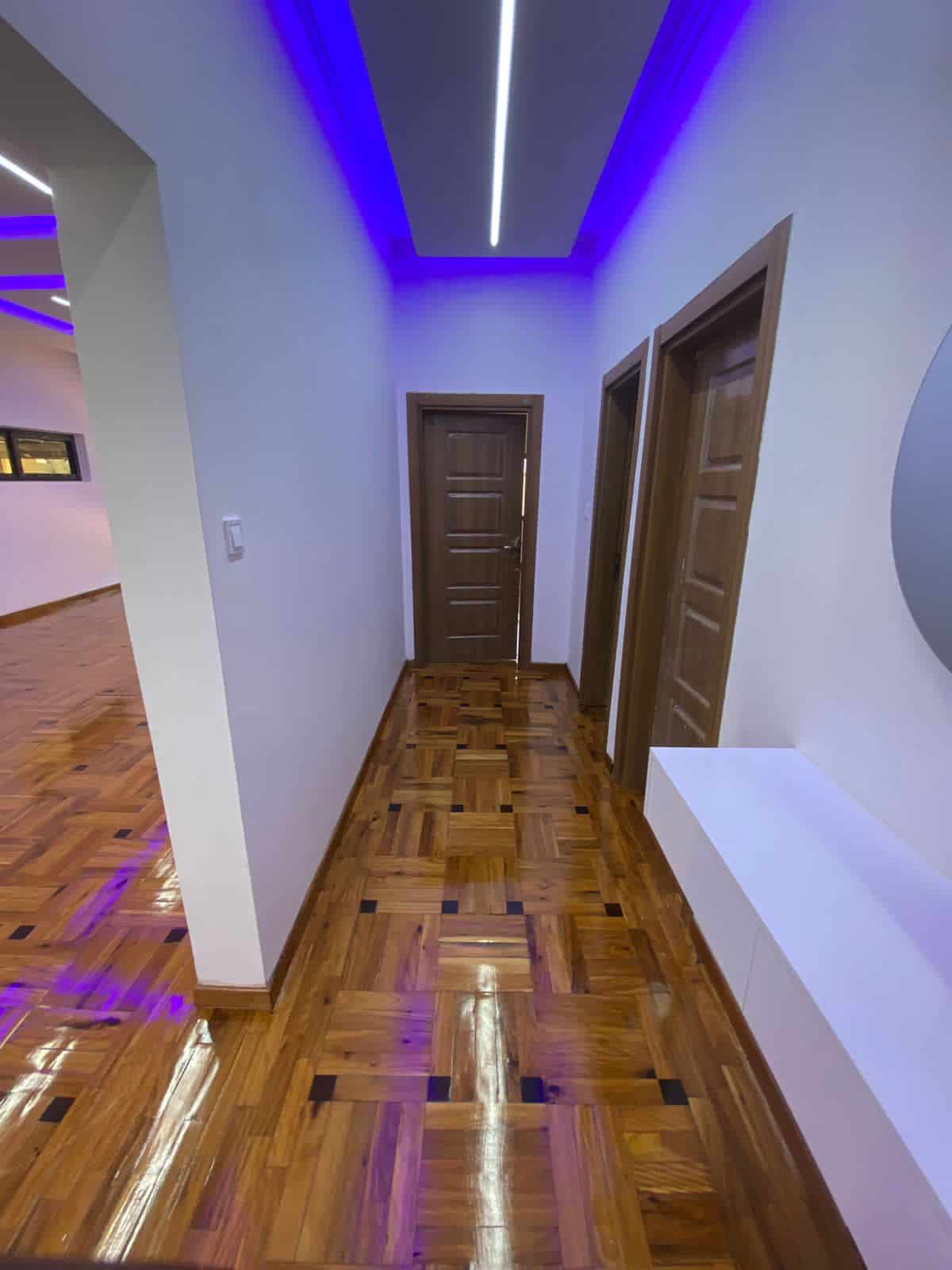 Contemporary interior hallway with wooden floors and vibrant LED lighting.