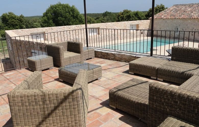 Elegant outdoor seating area with pool at Domaine de La Quiquier estate in Goudargues, France.