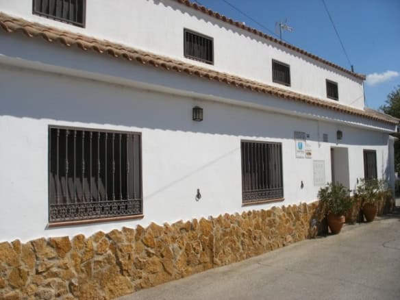 Cave house with white walls and black window bars in Cuevas del Campo, Granada, Spain.