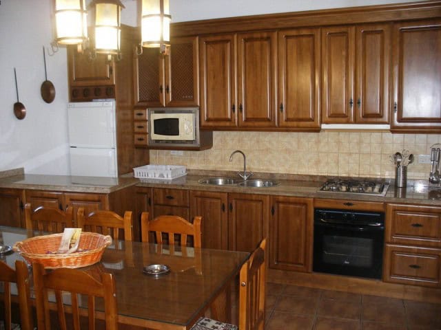 Charming cave house kitchen with wooden cabinets, modern appliances, and rustic decor in Cuevas del.