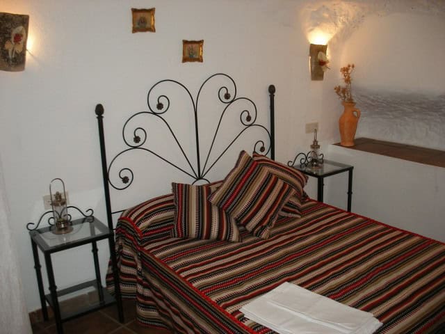 Charming cave house bedroom with traditional decor in Cuevas del Campo, Granada, featuring a wrought.