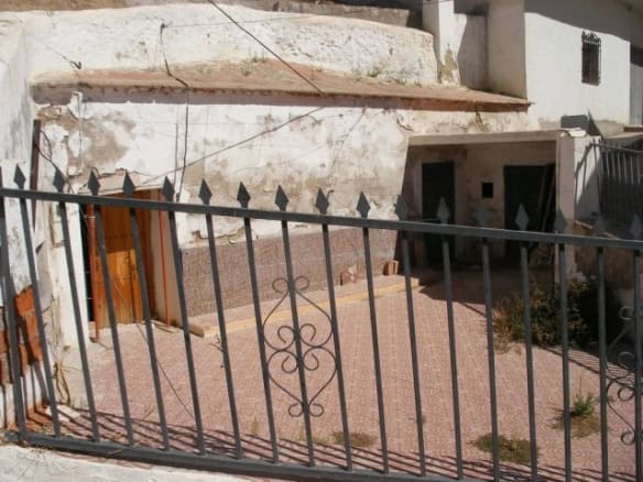 Cave house entrance with iron gate in Gorafe, Granada, showcasing unique underground architecture.