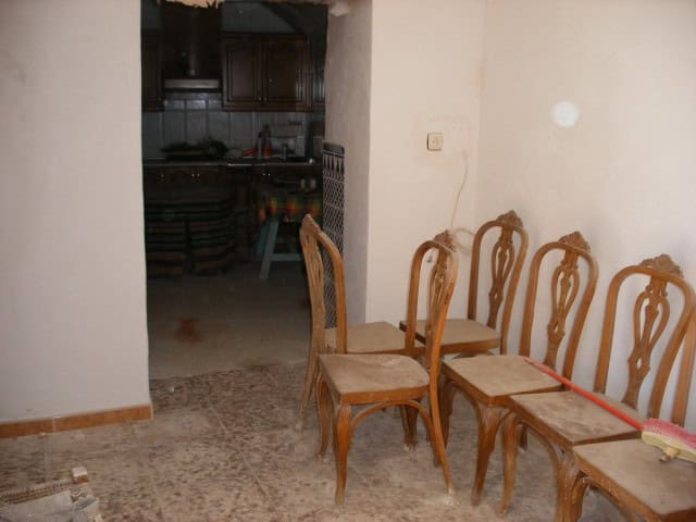 Charming interior of a cave house in Gorafe, Granada, featuring traditional wooden chairs and rustic.