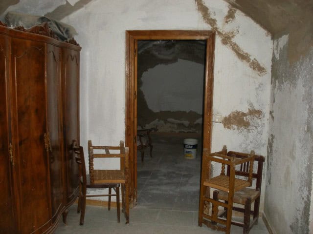 Unique cave house interior in Gorafe, Granada, showcasing rustic wooden furniture and natural stone.
