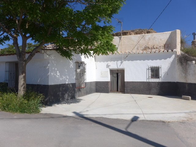 Cave house with white exterior walls and black base in Cortes de Baza, Granada, Spain.