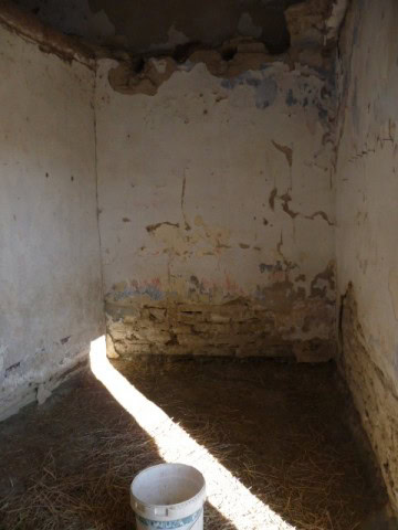 Abandoned rustic room with peeling walls and sunlight entering through a crack.
