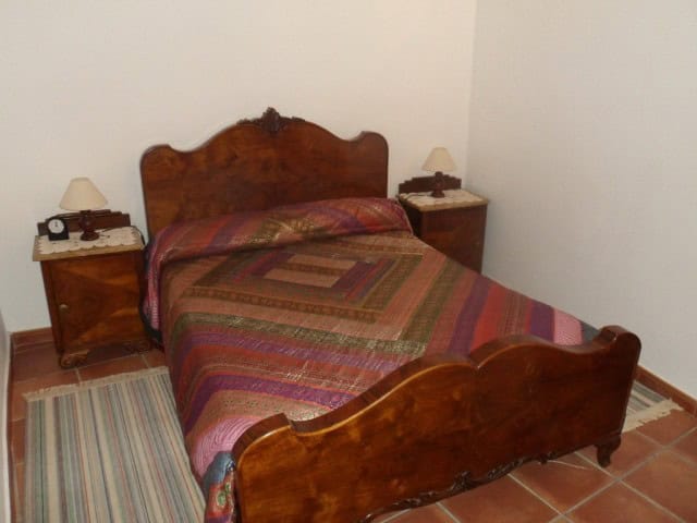 Village property bedroom with wooden furniture and colorful quilt in Benamaurel, Granada.
