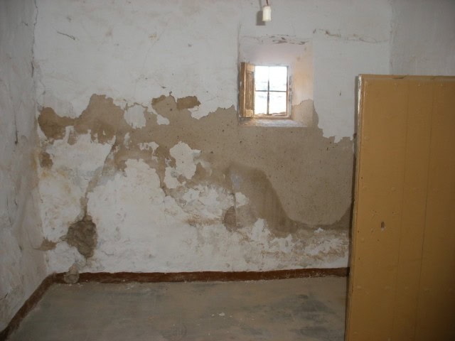 Charming village house in Venta del Peral, Granada, with rustic walls and small window.