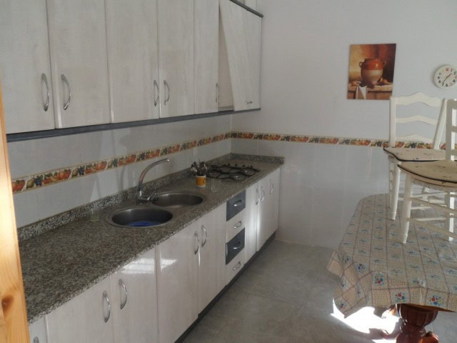 Charming kitchen of a village property in Cortes de Baza, Granada, featuring white cabinets and a gr.
