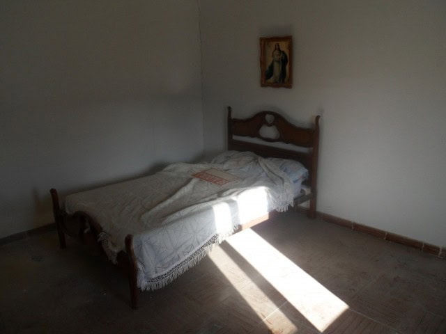 Village property bedroom with simple furnishings in Cortes de Baza, Granada. Bright sunlight illumin.
