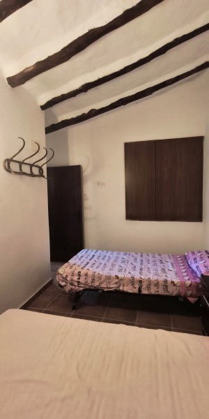 Cozy bedroom with rustic wooden beams and simple furnishings in a traditional village home.