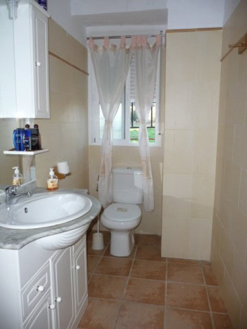 Bathroom with white sink, toilet, and window in Huesa village property.