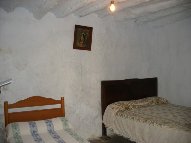 Cozy bedroom with rustic white walls and traditional wooden furniture in Velez Blanco, Almeria.