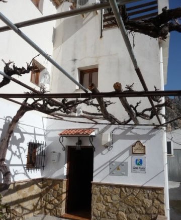 Charming village house in Belerda, Jaen with white walls and rustic stone accents.