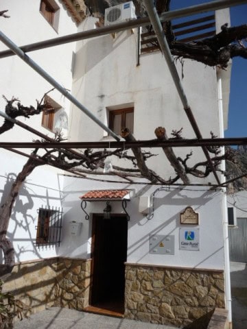 Charming village house in Belerda, Jaen with white walls and rustic stone accents.