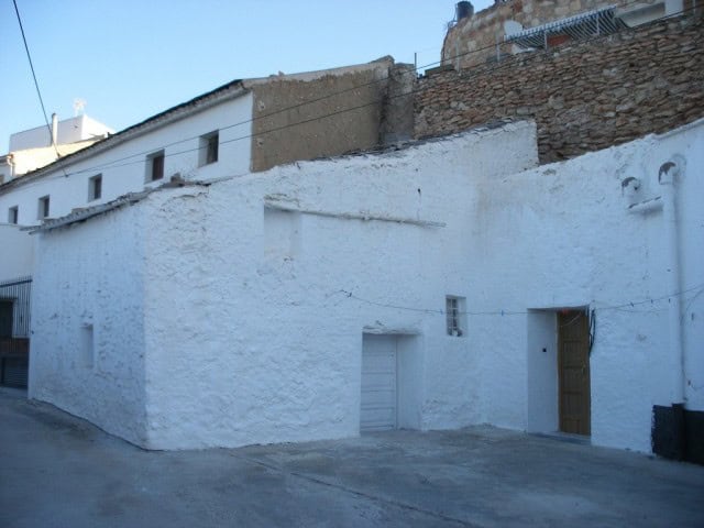 Traditional white cave house in Cuevas del Campo, Granada, with rustic stone accents and a simple wo.