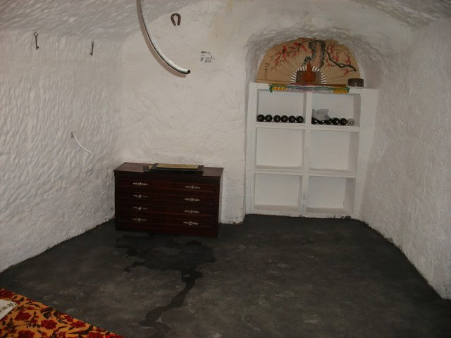 Cave house interior with whitewashed walls, wooden furniture, and decorative elements in Cuevas del.