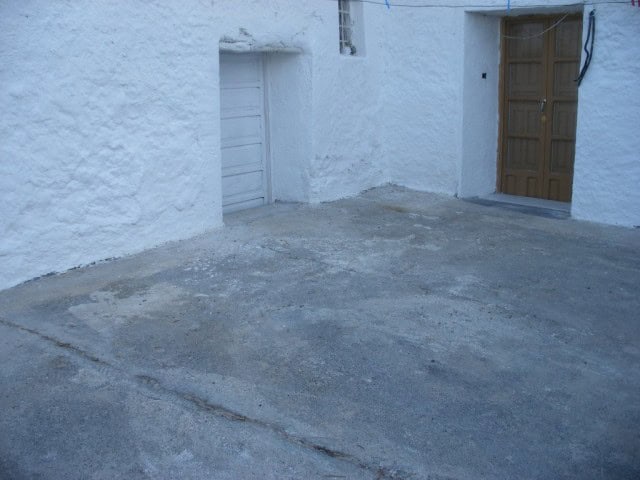 Cave house entrance with whitewashed walls and wooden door in Cuevas del Campo, Granada, Spain.