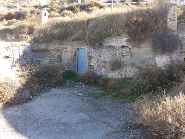 Cave house in Galera, Granada with rustic stone walls and a blue door.