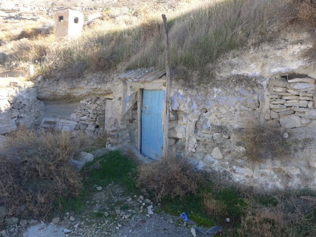 Cave house with blue door built into a hillside in Galera, Granada, Spain. Rustic and unique propert.