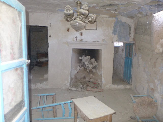 Cave house interior in Galera, Granada, with rustic walls, vintage chandelier, and traditional doors.