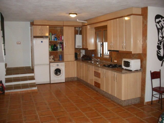 Charming rural home kitchen in Freila, Granada with wooden cabinets and modern appliances.