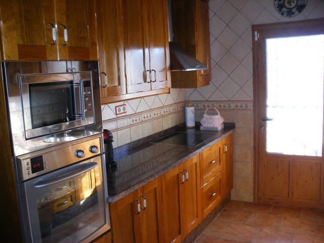 Spacious kitchen with wooden cabinets and modern appliances in a rural property in Freila, Granada.