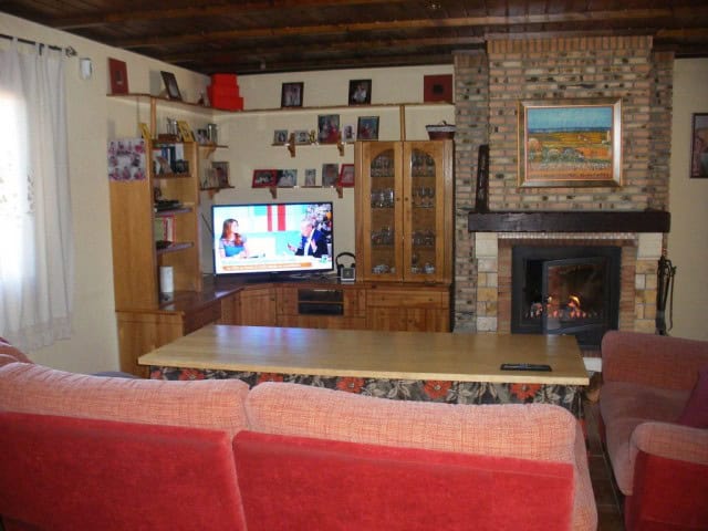 Charming living room featuring a brick fireplace, wooden shelves, and comfortable seating in a rural.