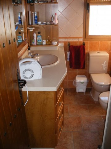 Bright bathroom with wooden accents and essential fixtures in a rural property.