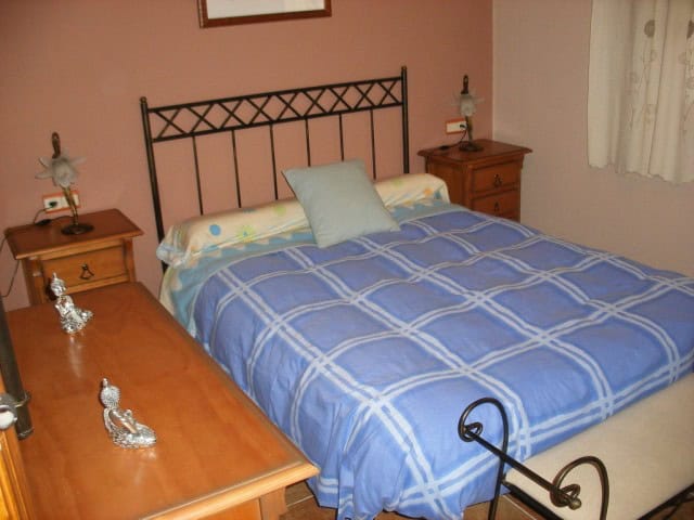 Cozy bedroom with a metal bed frame, blue checkered bedding, and wooden nightstands in a rural prope.