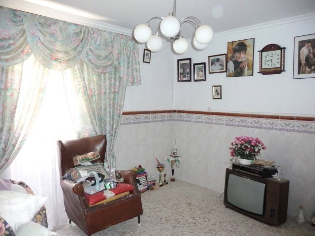 Charming village home interior in Larva, Jaen with vintage furniture, family photos, and cozy decor.