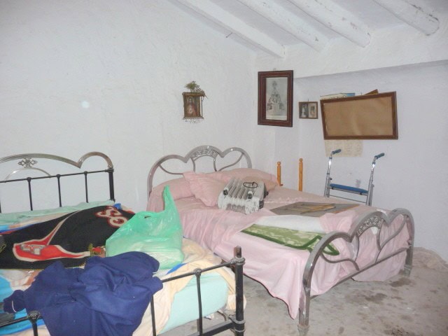 Village property interior with two beds, personal belongings, and mobility aids in Belerda, Jaen.