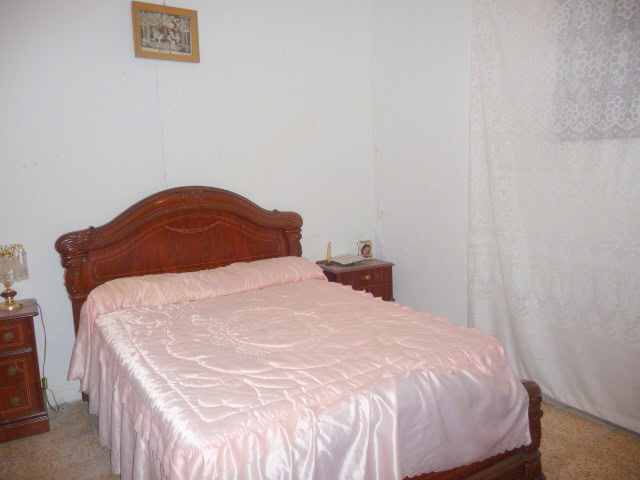 Comfortable bedroom with vintage wooden bed and soft pink bedding in Belerda, Jaen.