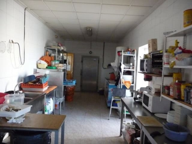Commercial kitchen storage room in Benamaurel, Granada with shelves and appliances.