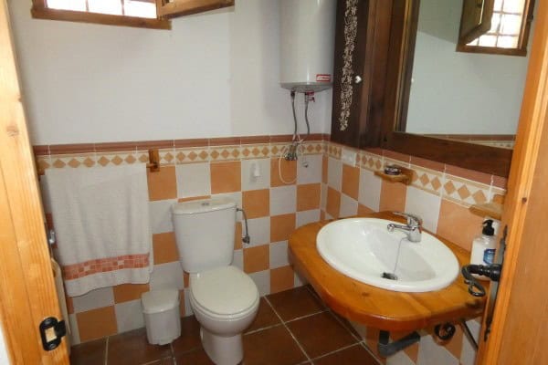 Interior view of a cave house bathroom in Galera, Granada with rustic wooden accents and tiled walls.