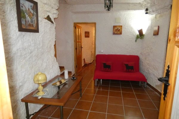 Interior of a cave house with white textured walls and terracotta tile flooring in Galera, Granada.