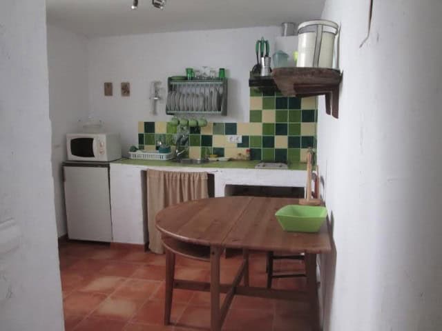 Village property kitchen with green tiled backsplash and basic appliances in Quesada, Jaen.