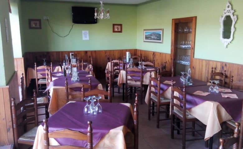 Interior view of a charming restaurant in Granada with wooden furniture and purple tablecloths.