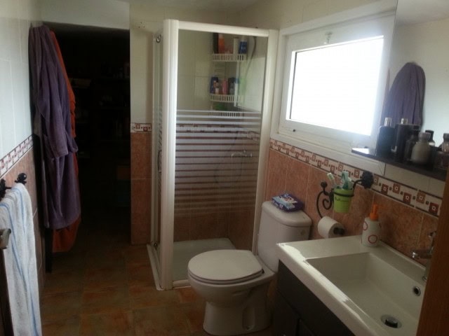 Bright bathroom with shower, toilet, and sink in a well-lit, modern setting.