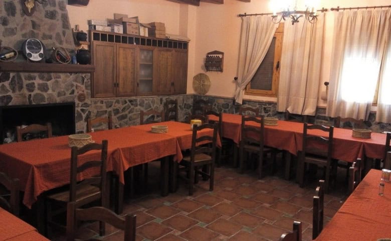Interior view of a traditional restaurant in Gor, Granada with rustic stone walls and wooden furnitu.