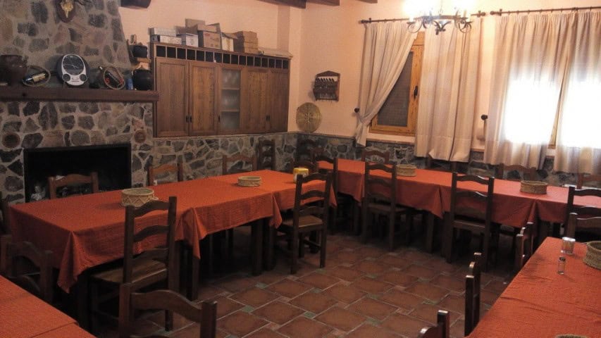 Interior view of a traditional restaurant in Gor, Granada with rustic stone walls and wooden furnitu.
