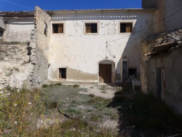 Ruin in Cuevas del Campo, Granada with weathered walls and small windows.