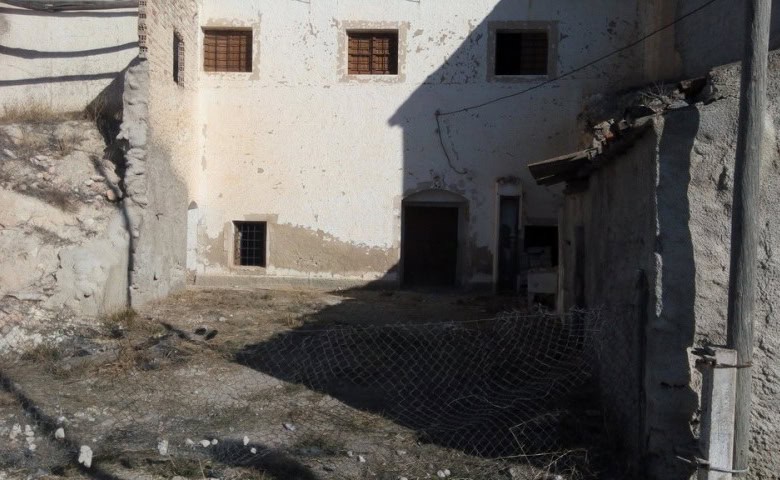Abandoned stone building ruin in Cuevas del Campo, Granada, with weathered walls and small windows.