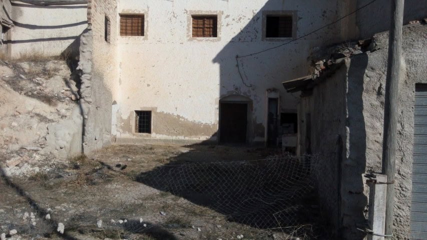 Abandoned stone building ruin in Cuevas del Campo, Granada, with weathered walls and small windows.