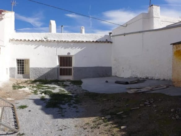 Cave house in Freila, Granada with white walls and rustic wooden door. Ideal for unique rural living.