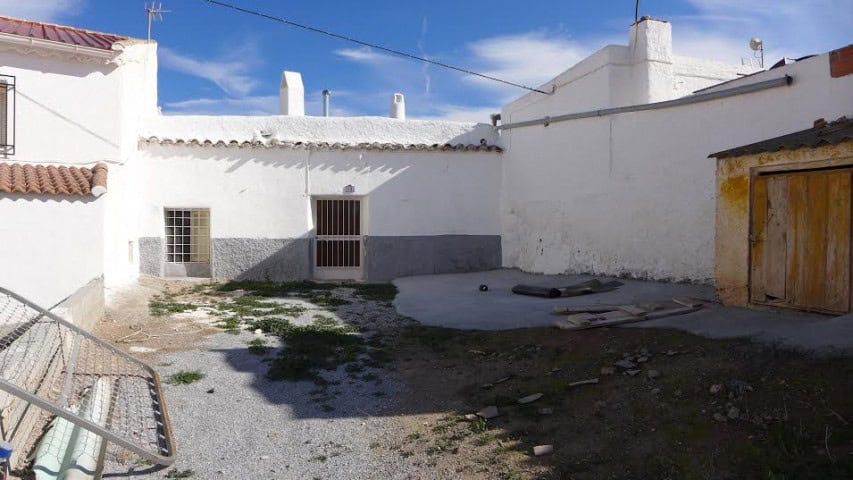 Cave house in Freila, Granada with white walls and rustic wooden door. Ideal for unique rural living.